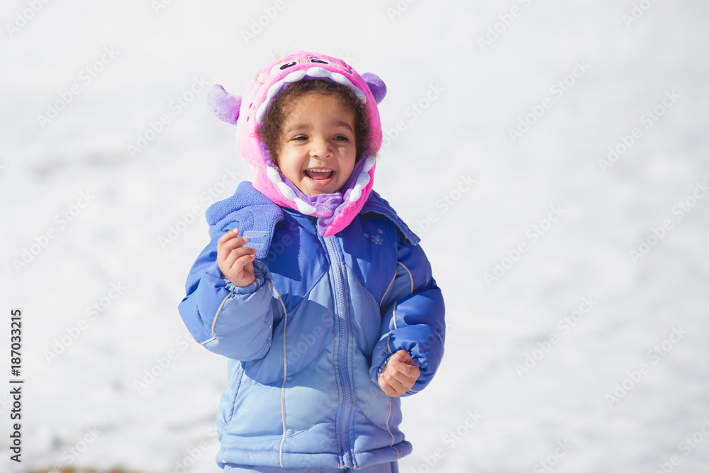 Young girl in a monster hat playing happily in the snow Young girl in a monster hat playing happily in the snow