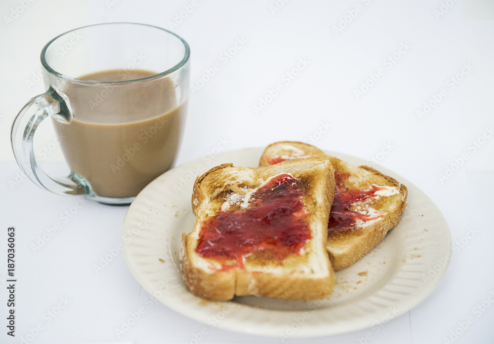 Toasted white bread is shown with jam and margarine next to a cup of coffee Toasted white bread is shown with jam and margarine next to a cup of coffee