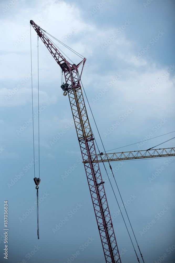Crane on construction site on cloudy blue sky background