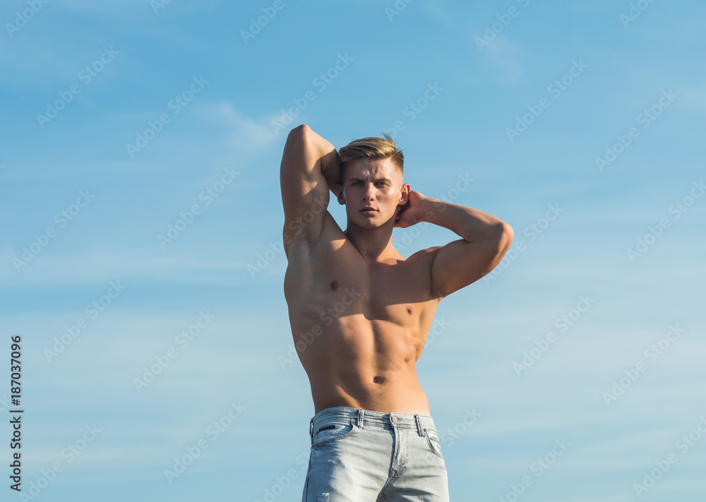 Macho show muscular torso in jeans on blue sky