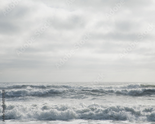 Breaking waves beneath overcast sky photo