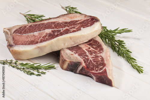 стейк мясо на кости с веточкой розмарина и тимьяна на белом фоне 