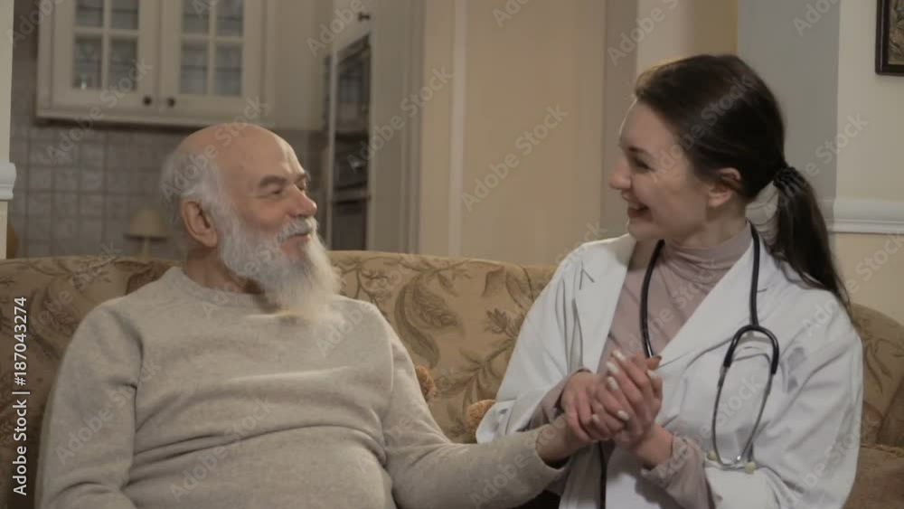 Health visitor talks with senior man at the sofa Health visitor talks with senior man at the sofa
