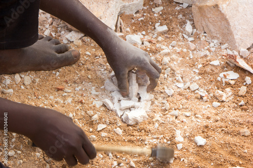 Canvas-taulu Ugandan child's hands breaking rocks into small slabs for his or her foreman