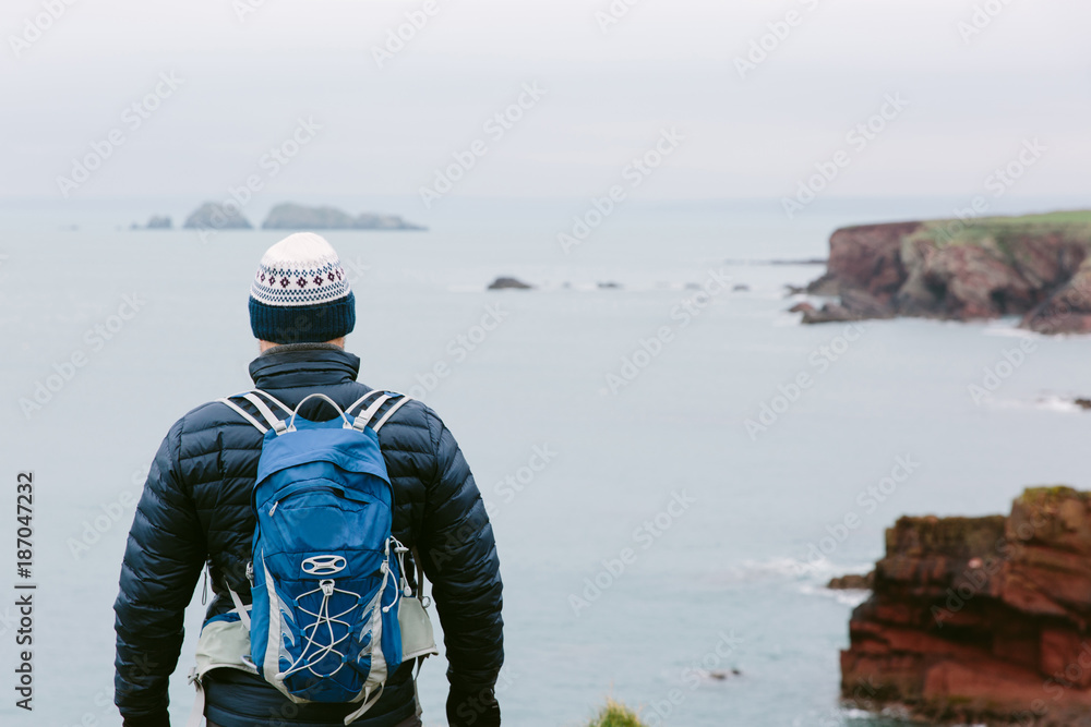 Male hiker standing looking out to sea. Male hiker standing looking out to sea.
