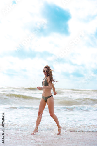 happy girl on the beach with a beautiful figure in a swimsuit. a trip to the sea around the world 