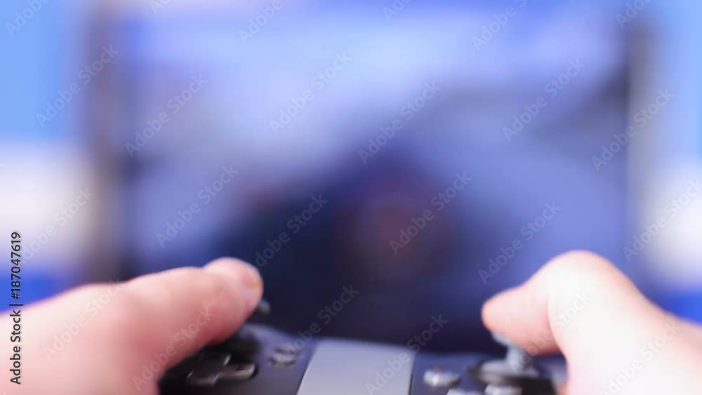 Man holds a gaming controller in his hands and plays games on a large monitor. Man holds a gaming controller in his hands and plays games on a large monitor.