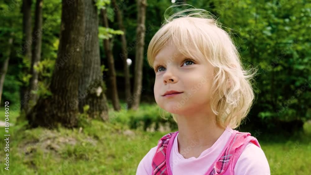 Little blonde girl eating a meal and nodding head in the summer park. 4K Little blonde girl eating a meal and nodding head in the summer park. 4K