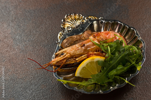 One Fried Tiger Prawn or langostino with greens and Lemon on ancient plate