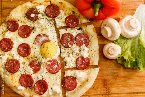 Fresh pizza with tomatoes, cheese and mushrooms on wooden table closeup.