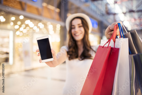 With the phone the purchase is easier. A woman is holding a phone with a place for advertising in the mall