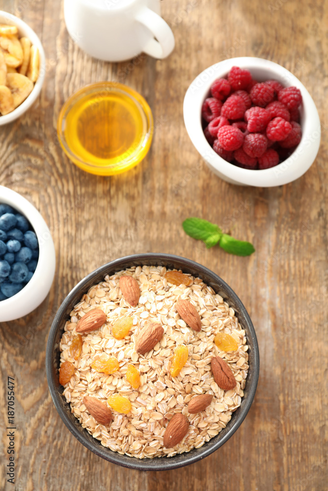 Bowl with oatmeal flakes, raisins and almond on wooden background
