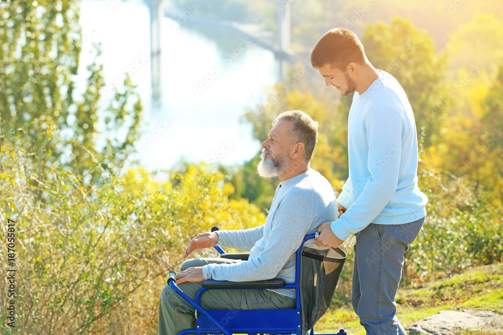 Young caregiver walking with senior man in park Young caregiver walking with senior man in park