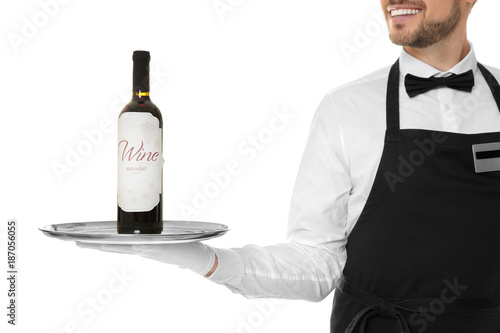 Handsome waiter holding metal tray with bottle of wine on white background © Africa Studio