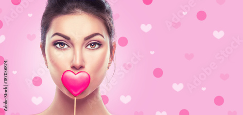 Valentine's Day. Beauty young fashion model girl with Valentine heart shaped cookie over pink background