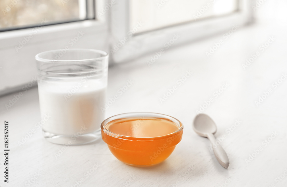 Glass of milk and bowl with honey on windowsill Glass of milk and bowl with honey on windowsill