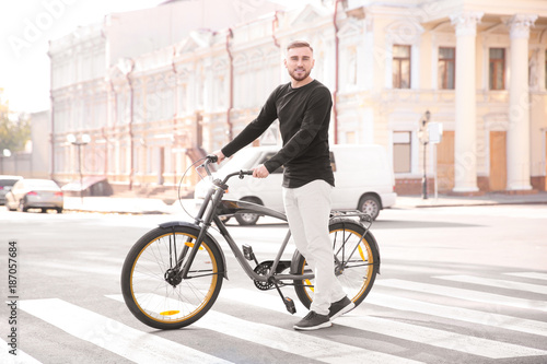 Handsome young hipster man with bicycle on crosswalk
