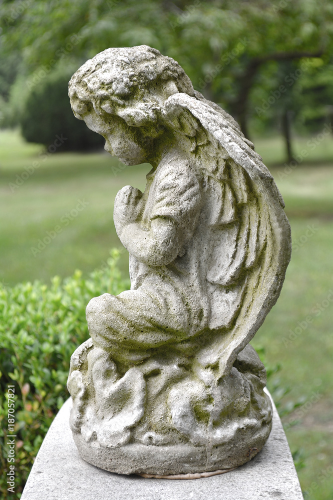 Sad angel marble sculpture. Symbol of eternity, life and death. Antique statue of religion and faith. Vintage image of stone angel in a cemetery.
