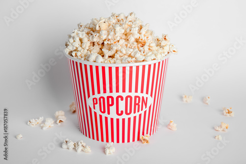 Striped bucket with tasty popcorn on white background