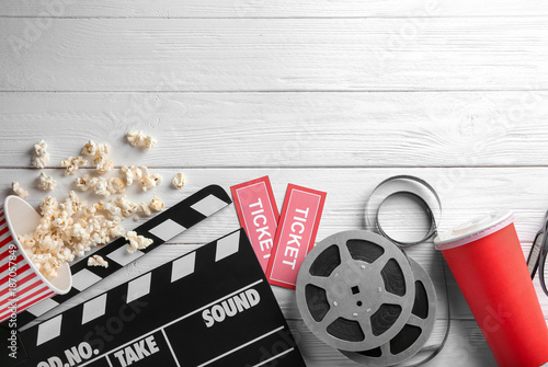 Tasty popcorn, movie reel, tickets and clapboard on wooden background