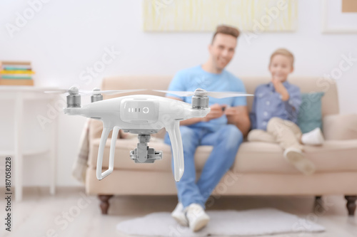 Cute boy and his father playing with drone at home