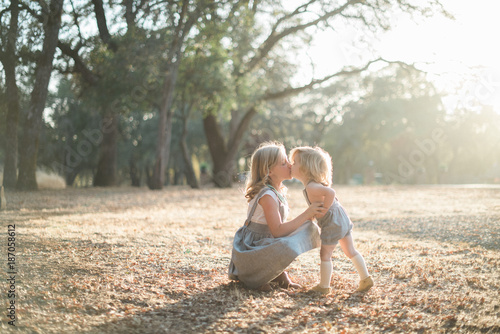 Two young children kissing in a park