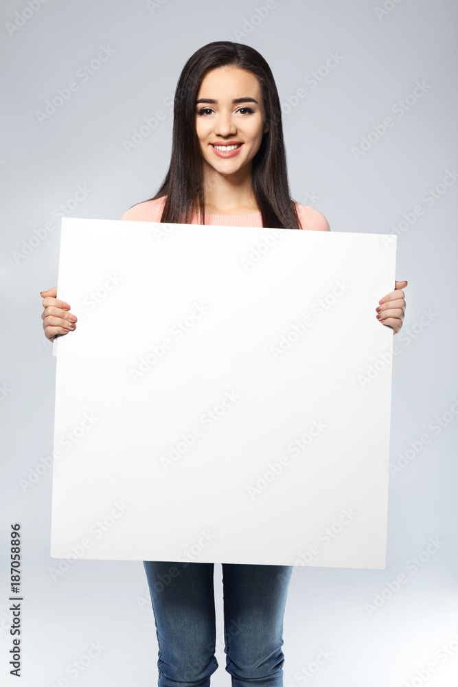 Young woman with blank advertising board on light background Young woman with blank advertising board on light background
