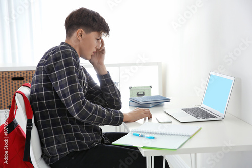 Upset teenage boy with lapt...