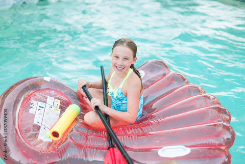 Portrait of smiling girl floating on pool toys in swimming pool