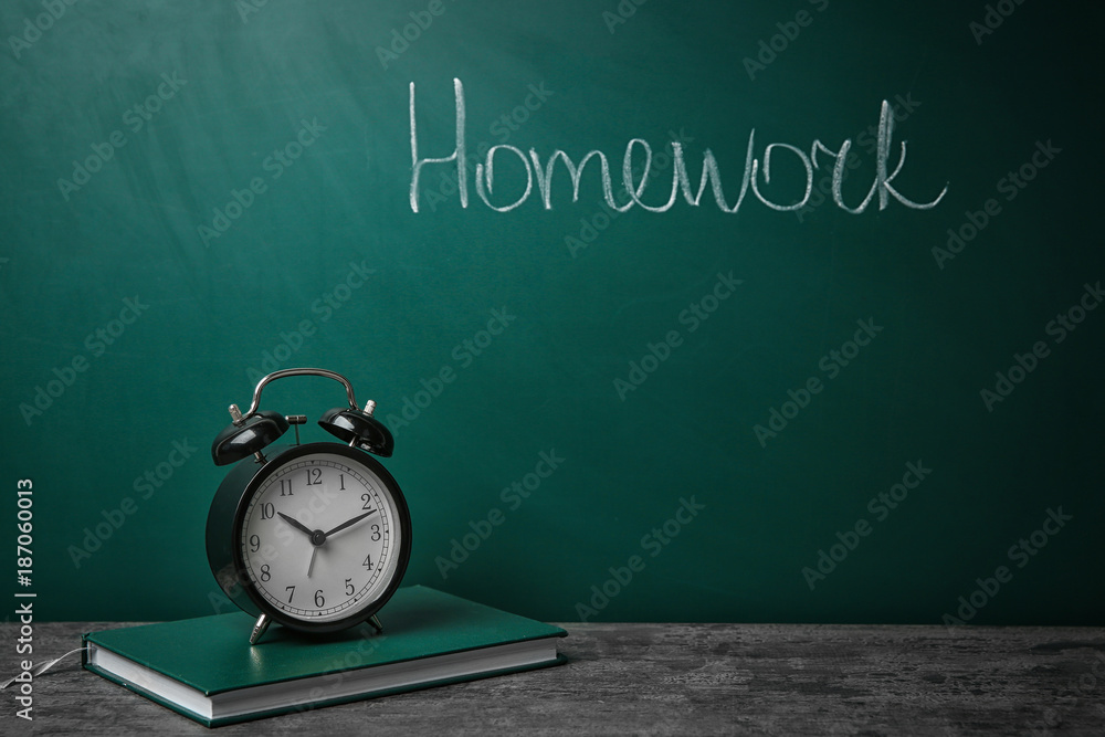 Notebook and alarm clock on table near chalkboard with word Notebook and alarm clock on table near chalkboard with word