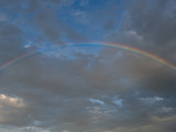 A rainbow arcs through the clouds.