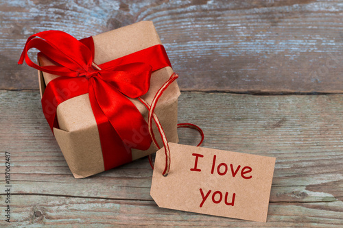 Gift box on the wooden background. Red ribbon. Valentine's Day gift photo