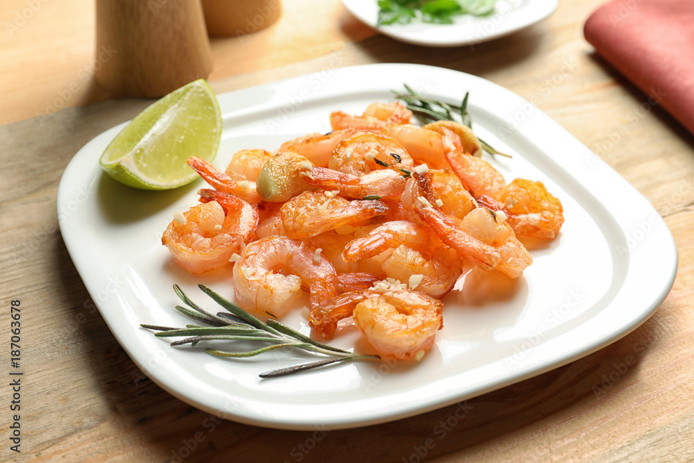 Plate with delicious fried shrimps and garlic on table Plate with delicious fried shrimps and garlic on table