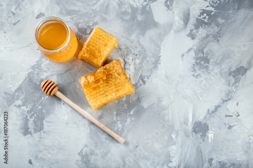 Composition with sweet honey, dipper and honeycombs on grey background