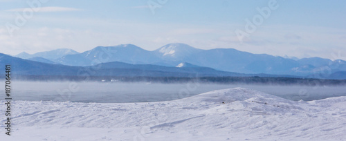 frigid winter morning with misty steam rising off the lake with the Adirondack mountains across the lake in New York 
