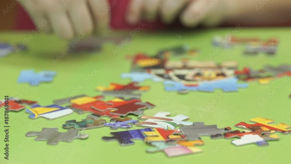 Close-up of hands of little unidentified child collecting picture from puzzles at the table in kindergarten Close-up of hands of little unidentified child collecting picture from puzzles at the table in kindergarten