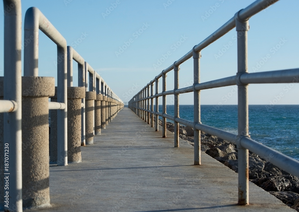 Pier structure with perspective towards the ocean horizon.