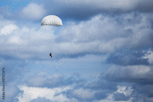 Parachutist descending from above with a white canopy