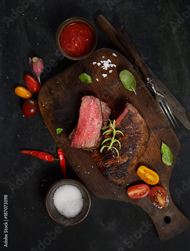 grilled steak with rosemary on a cutting board on a wooden background