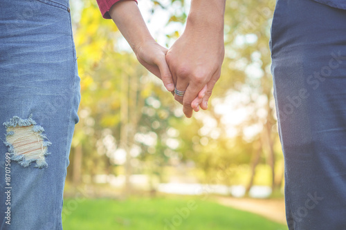 young couple in love holding hand together walking in a beautiful park with romantic nature background 