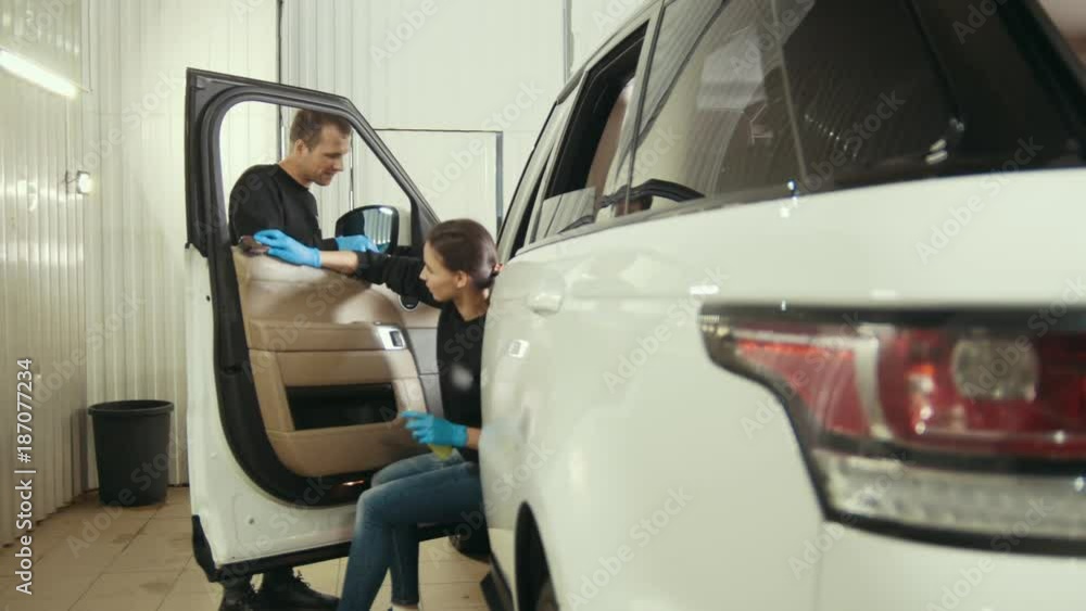 Young girl and man in gloves is washing a car interior and door Young girl and man in gloves is washing a car interior and door
