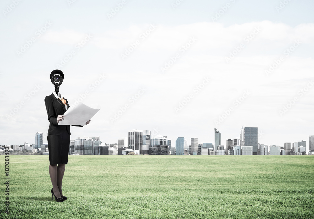 Camera headed woman standing on green grass against modern citys