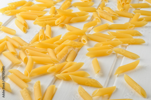 A lot of pasta is scattered on a white wooden table. The concept of eating. photo