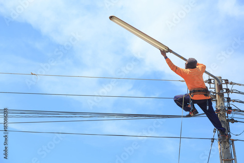 electrician repairing high voltage power lines and replacing bulb