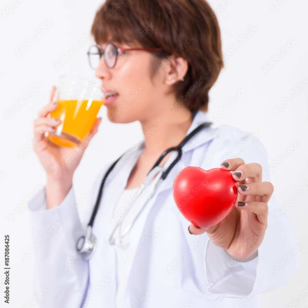Happy woman doctor holding the red heart and orange juice. Isolated on white background. Studio lighting. Concept for healthy and medical Happy woman doctor holding the red heart and orange juice. Isolated on white background. Studio lighting. Concept for healthy and medical