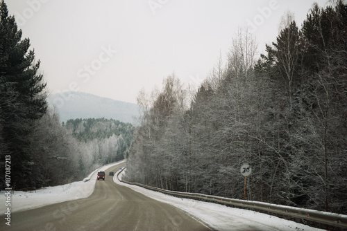 Snowy winter road among frozen forest after sleet. Cold weather, snowstorm, bad visibility. Moscow area.