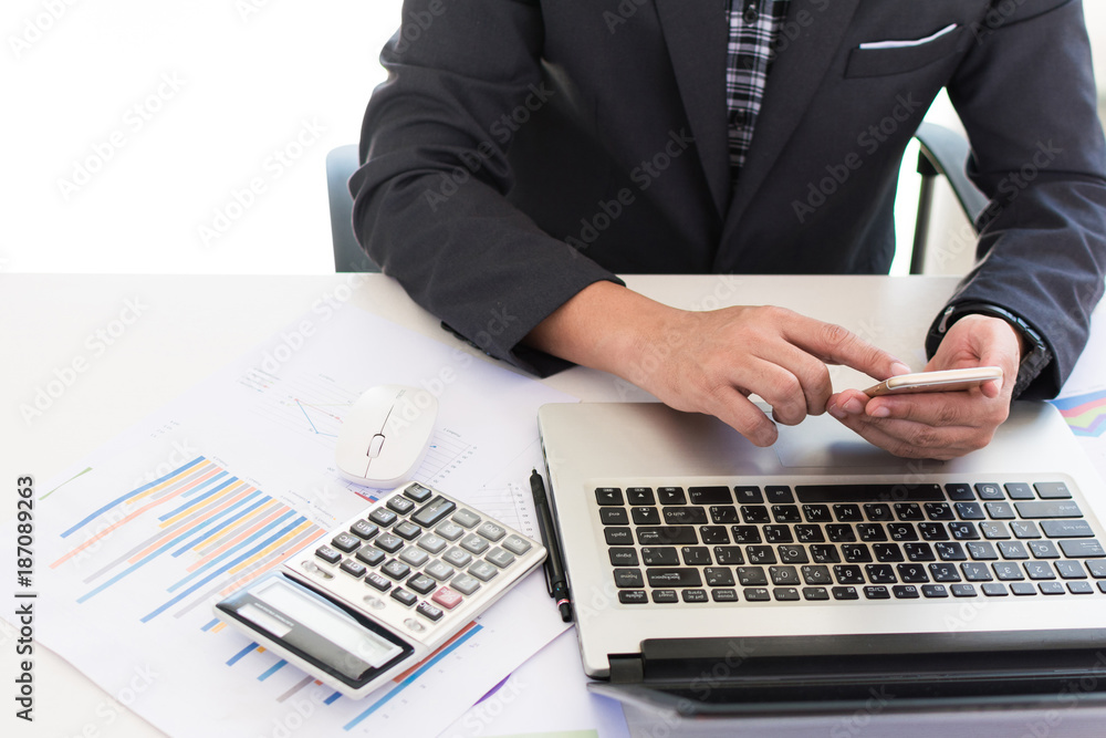 Business man using a smart phone on wooden table with laptop on white background. Work office work space concept. Business man contact with a partner. Concept of online payment shopping. Business man using a smart phone on wooden table with laptop on white background. Work office work space concept. Business man contact with a partner. Concept of online payment shopping.
