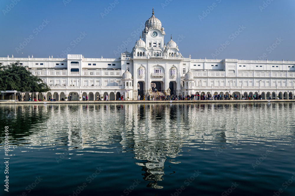 White building of Central Sikh Museum, Amritsar, India. .Reflection of famous Indian landmark at the water of sacred pond on sunny day.