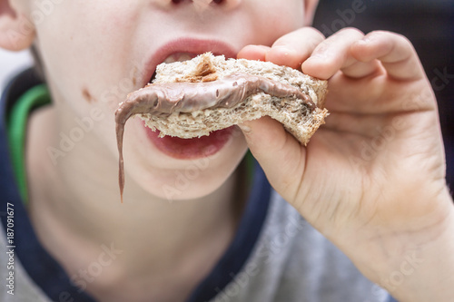 Closeup of boy eating sweet sandwich with chocolate