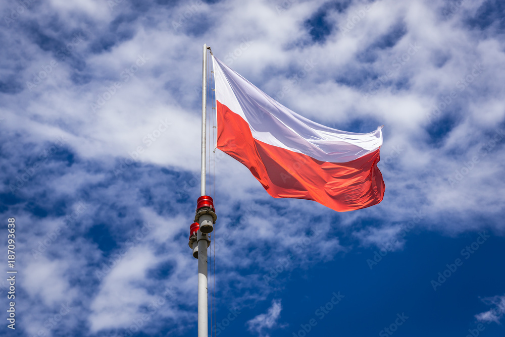 Polish flag against blue sky and white clouds, Pilsudski Mound in Cracow